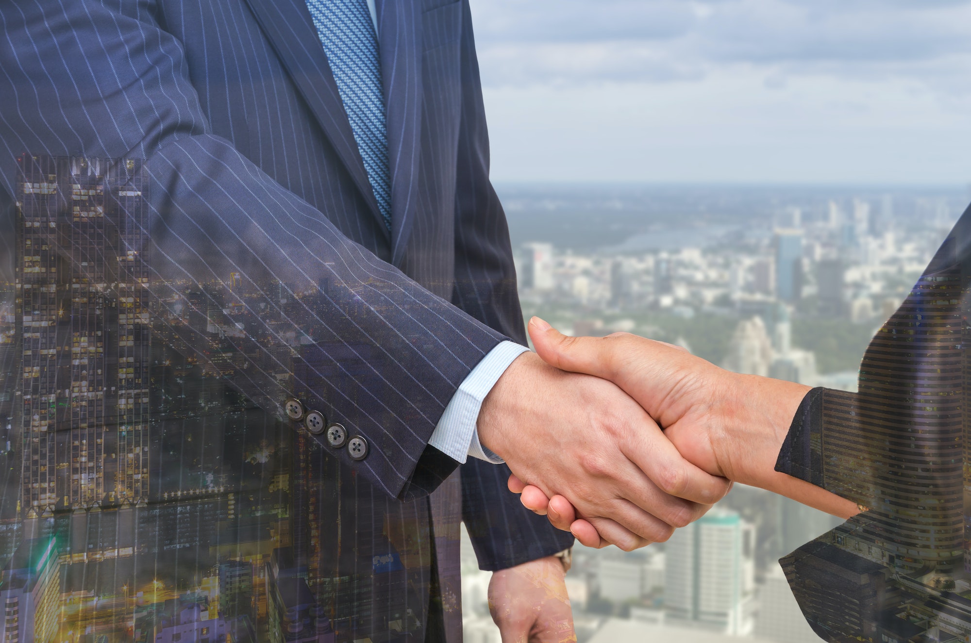 Double exposure handshake between businessman on cityscape background, Business concept